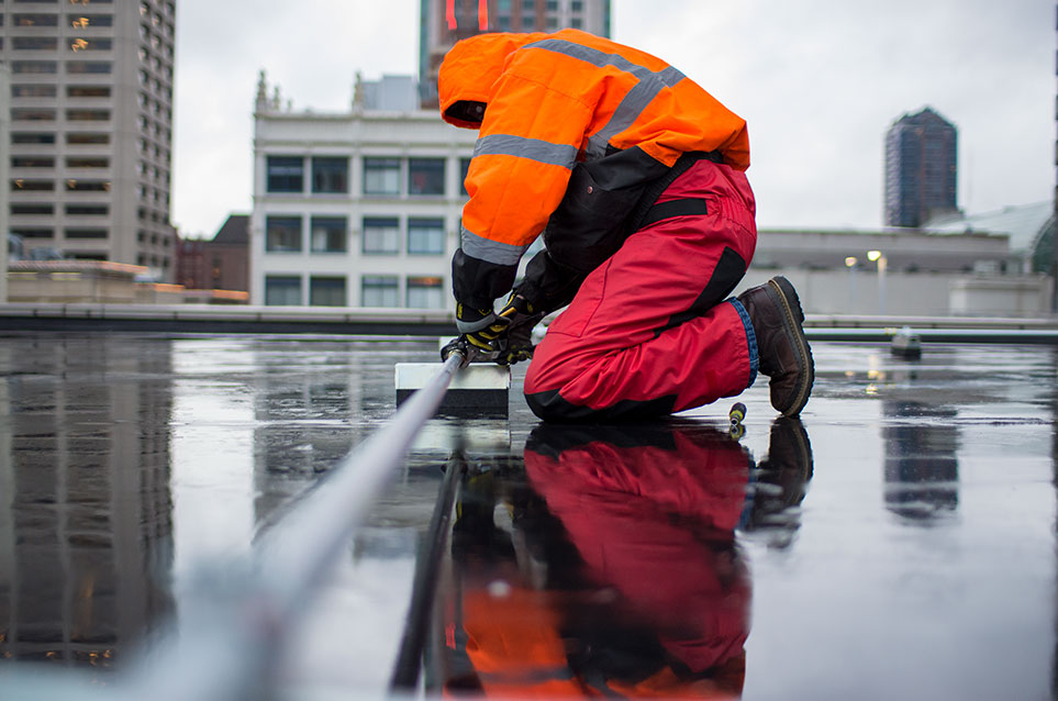 Field Technician running wire through a pipe on a rooftop